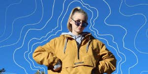 Gabby Petito in a yellow pullover in front of a blue sky