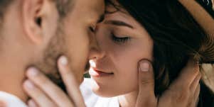 man and woman holding each other's faces leaning in to kiss