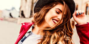 Woman on street smiles and tosses her hair