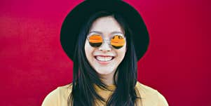 vibrant young woman in sunglasses against red backgrond