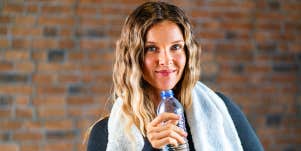 Young woman drinks water after workout