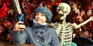 kid with skeleton decoration taking picture to post on Instagram