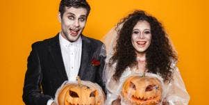 couple in halloween wedding attire holding pumpkins