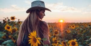 woman at sunset surrounded by sunflowers