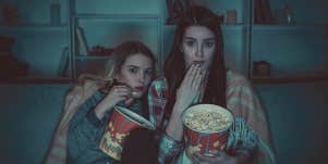 two people holding pop corn , looking scared