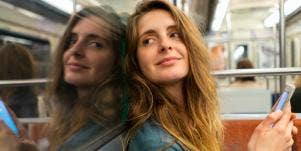 woman smiling on subway holding phone