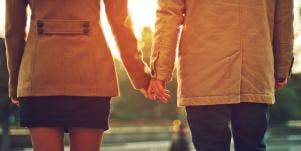 man and woman holding hands in sunset