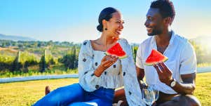 man and woman having picnic eating watermelon