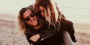 woman piggybacking on man on beach