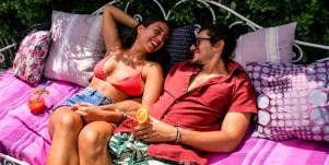 man and woman lounging on pink blanket smiling in the sun