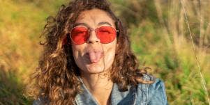 woman sticking her tongue out wearing red sunglasses