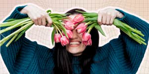 Woman smiling holding flowers over her eyes 
