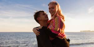 man carrying girlfriend on beach