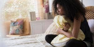 girl sitting on bed trying not to text her ex