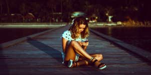 girl sitting on the ground breaking up with someone over text