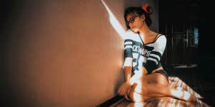 sad woman sitting on bedroom floor listening to music