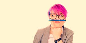 Pink haired woman distracts herself by balancing pencil on upper lip