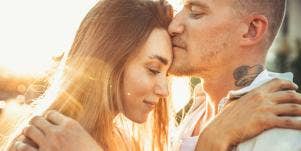 man kissing woman's forehead