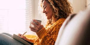 smiling woman writing and having coffee