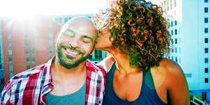 woman sitting next to man and kissing his forehead