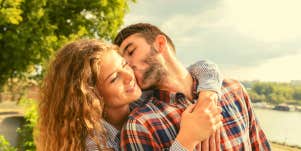woman hugging man while he turns around to kiss her