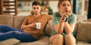 couple sitting on couch bored looking at TV