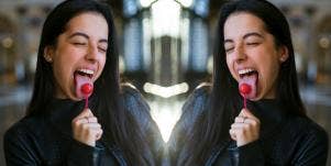 woman with tongue out licking lollipop