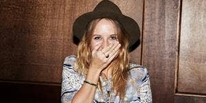 embarrassed looking woman with hand over her mouth