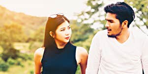young Asian couple looks at one another in sunlight