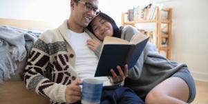 man and woman reading together on couch