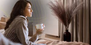 female reflecting out window with coffee in her cup