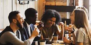 racially diverse group of adults talking over pizza dinner