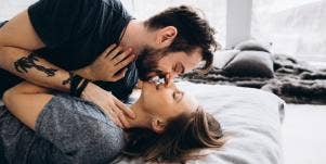 man and woman laying on a bed kissing