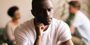 frustrated man sits alone in room of people