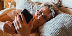 old woman looking at phone in bed