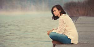 woman by water, sitting alone