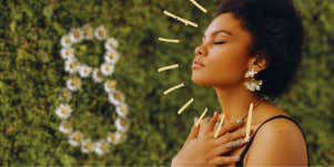 woman meditating with grass and a figure 8 in daisies in the background