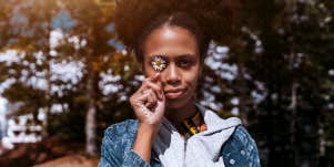 woman holding flower in front of eye