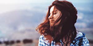 woman with dark reddish hair has a pensive winter thought, in the wind