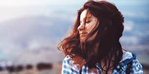 woman with dark reddish hair has a pensive winter thought, in the wind