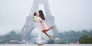 man with woman in his arms in front of the Eiffel tower