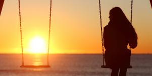 woman on swingset with sunset