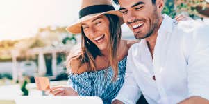 man and woman smiling while looking at laptop