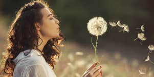 woman wishing on dandelion