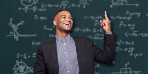 happy man in front of chalkboard with physics problems on it