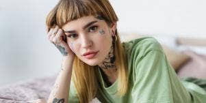 tattooed woman wearing green in bed