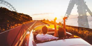 Couple driving on a road roller coaster in background