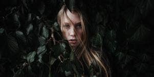 woman with a life out of balance hiding behind leaves 
