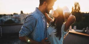 woman and man embracing with sunset behind them