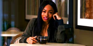 woman sitting at table drinking coffee alone
